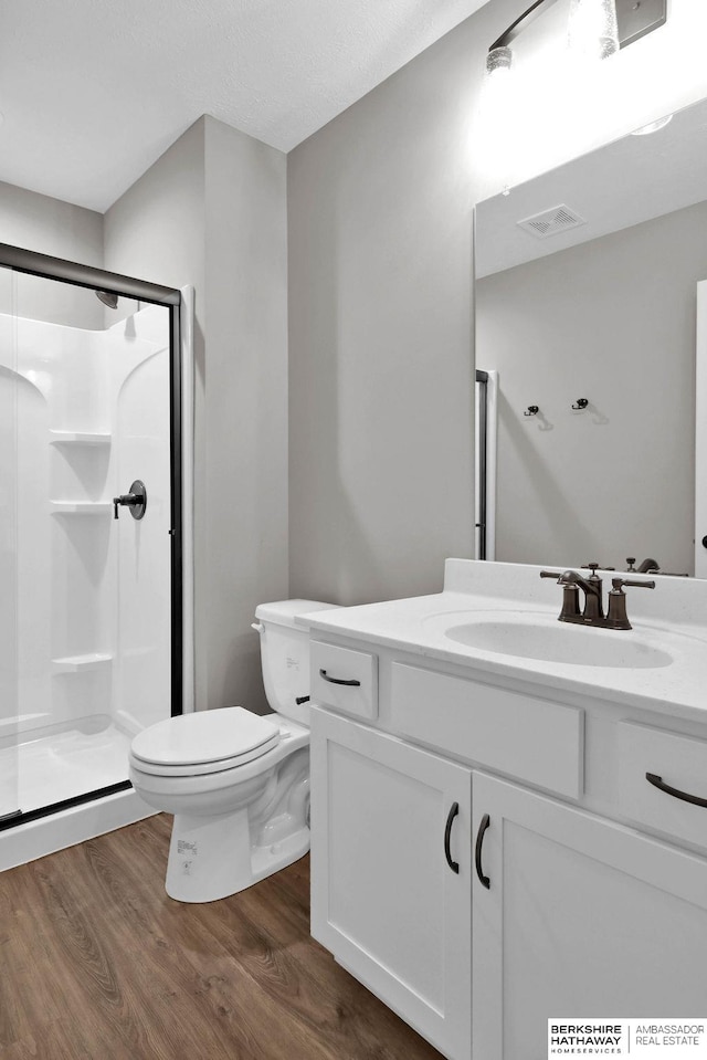 bathroom with vanity, hardwood / wood-style flooring, toilet, and a shower with door