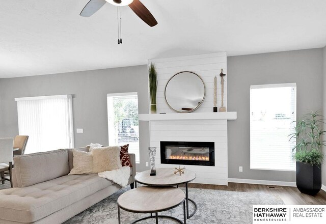 living room featuring a fireplace, light wood-type flooring, and ceiling fan