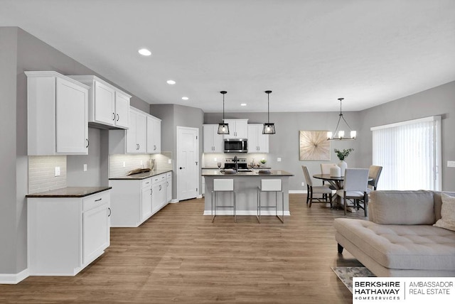 kitchen featuring hanging light fixtures, decorative backsplash, a kitchen island, white cabinetry, and stainless steel appliances