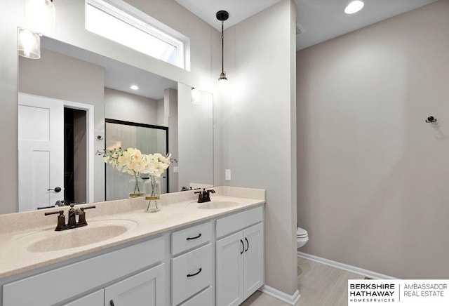 bathroom with vanity, toilet, and a shower with door