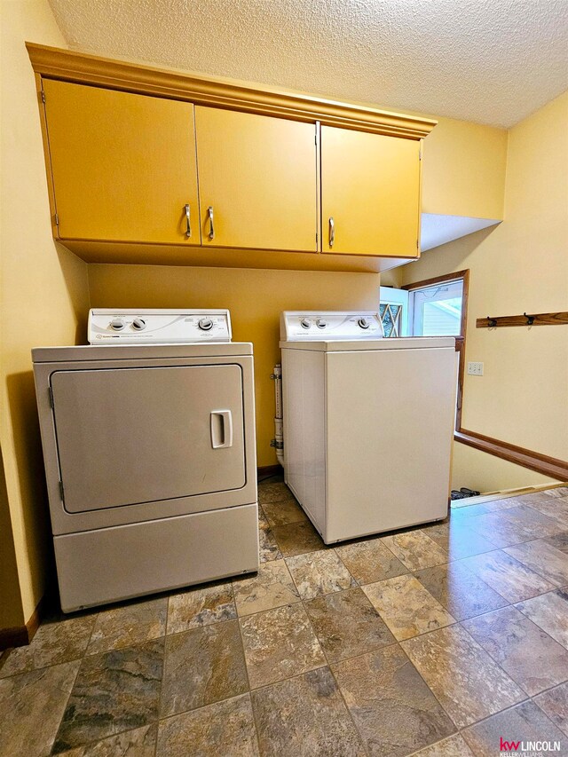 washroom featuring washing machine and dryer, a textured ceiling, cabinets, and tile patterned flooring