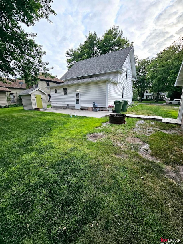 back of property with a lawn, a patio area, and a storage unit