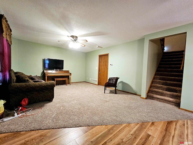 living room featuring ceiling fan, a textured ceiling, and wood-type flooring