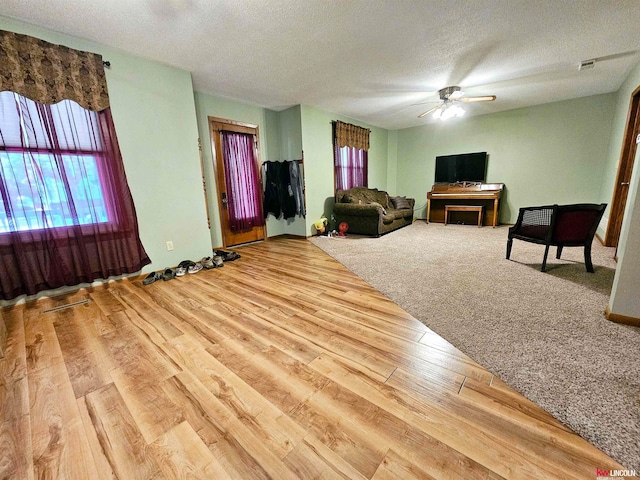 living room featuring ceiling fan, a textured ceiling, and light carpet