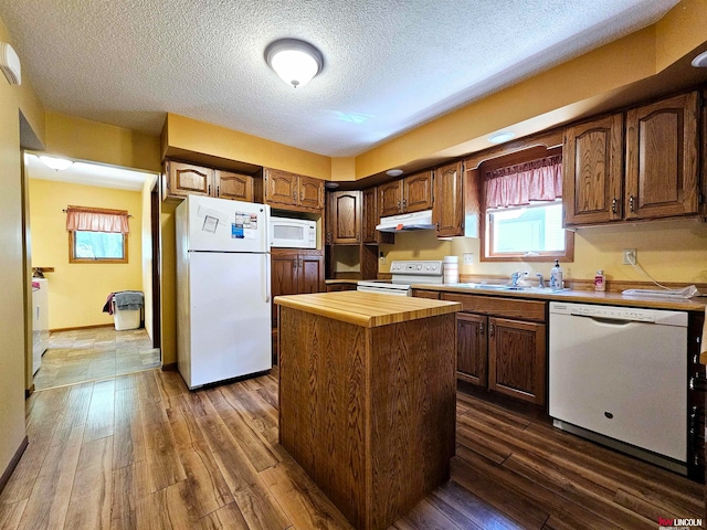 kitchen with dark hardwood / wood-style flooring, a textured ceiling, white appliances, and a center island