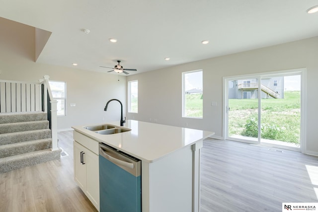 kitchen with a center island with sink, stainless steel dishwasher, light hardwood / wood-style floors, white cabinets, and sink