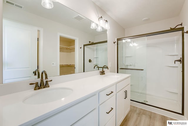 bathroom with double sink vanity, an enclosed shower, and hardwood / wood-style floors