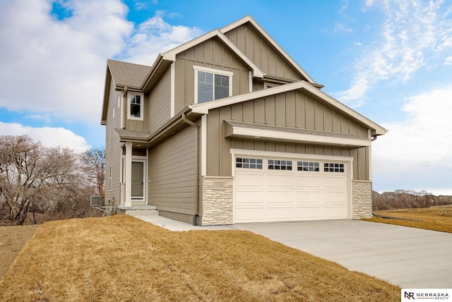 craftsman-style house featuring board and batten siding, a front yard, stone siding, and driveway