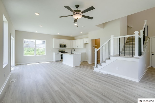 unfurnished living room featuring ceiling fan, sink, and light hardwood / wood-style floors