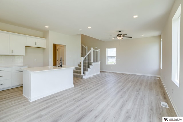 kitchen featuring a wealth of natural light, tasteful backsplash, ceiling fan, and light hardwood / wood-style floors