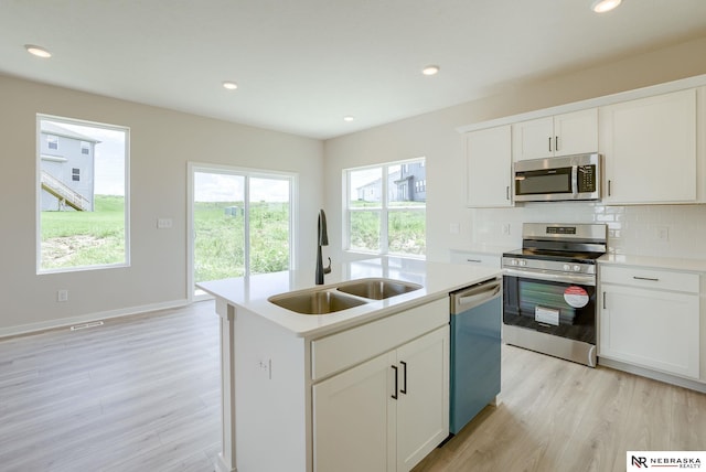 kitchen with appliances with stainless steel finishes, sink, decorative backsplash, and a healthy amount of sunlight