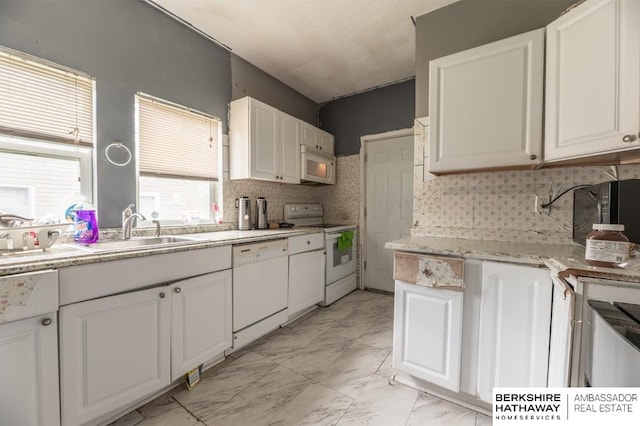 kitchen featuring white appliances, white cabinets, light tile patterned flooring, and backsplash