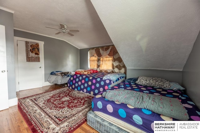 bedroom with ceiling fan, light hardwood / wood-style flooring, a textured ceiling, and lofted ceiling