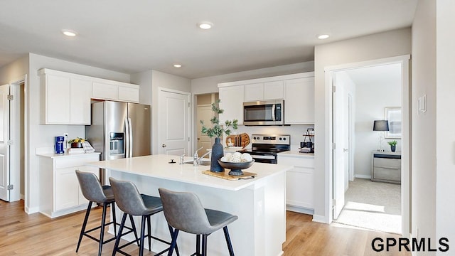 kitchen with white cabinetry, a kitchen bar, an island with sink, and appliances with stainless steel finishes