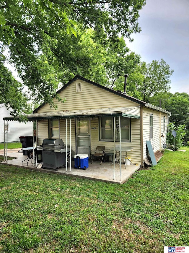 back of house with a lawn and a patio