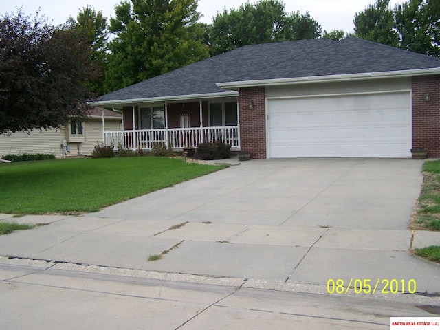 ranch-style house featuring a front lawn, a garage, and covered porch