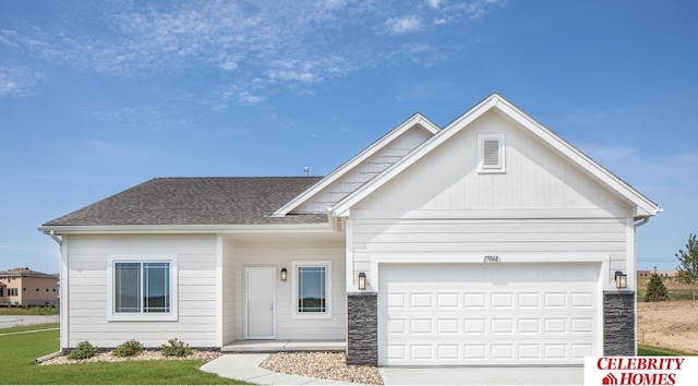 view of front facade with a garage, a shingled roof, concrete driveway, stone siding, and board and batten siding