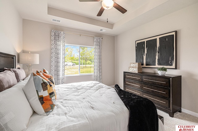 bedroom with a raised ceiling, visible vents, and light colored carpet