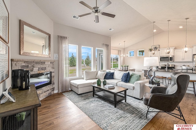 living room with visible vents, a fireplace, high vaulted ceiling, and wood finished floors