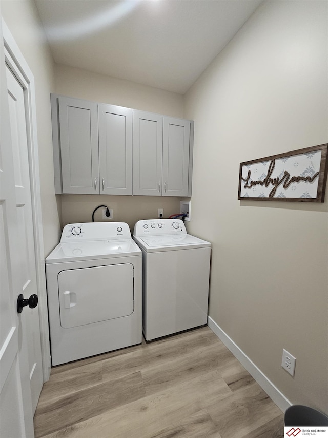 laundry room with cabinets, washer and dryer, and light hardwood / wood-style flooring