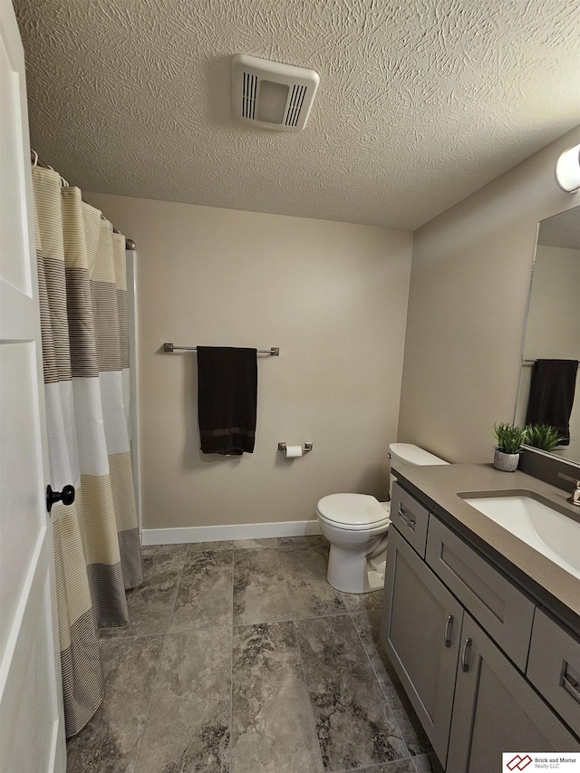 bathroom with vanity, a textured ceiling, and toilet