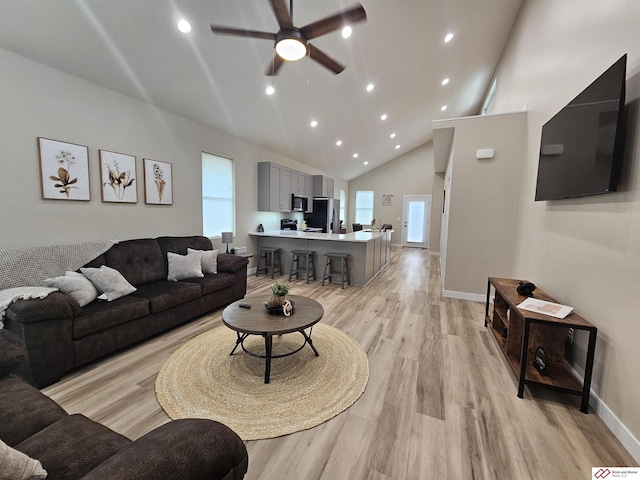 living room featuring ceiling fan, a wealth of natural light, high vaulted ceiling, and light hardwood / wood-style flooring