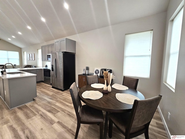 dining space featuring lofted ceiling, sink, a wealth of natural light, and light wood-type flooring