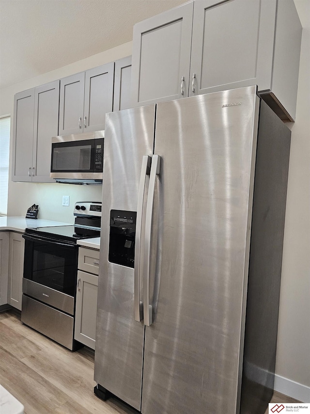 kitchen with stainless steel appliances, light wood-type flooring, and gray cabinetry