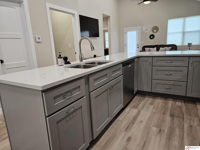 kitchen featuring gray cabinets, dishwasher, sink, and light wood-type flooring