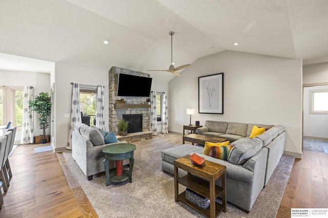 living room featuring a fireplace, vaulted ceiling, wood-type flooring, and ceiling fan