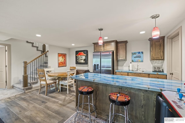 kitchen with dark hardwood / wood-style flooring, decorative light fixtures, a kitchen breakfast bar, and stainless steel refrigerator with ice dispenser