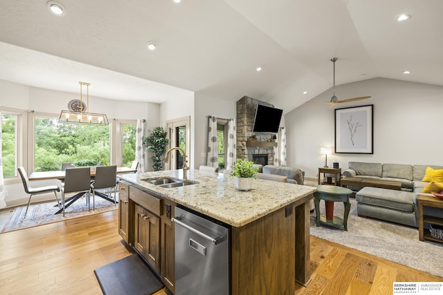 kitchen featuring decorative light fixtures, dishwasher, an island with sink, sink, and light hardwood / wood-style flooring