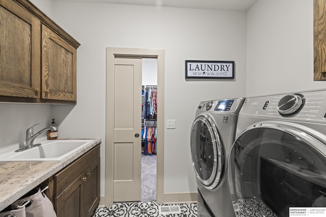 washroom featuring sink, washing machine and dryer, and cabinets