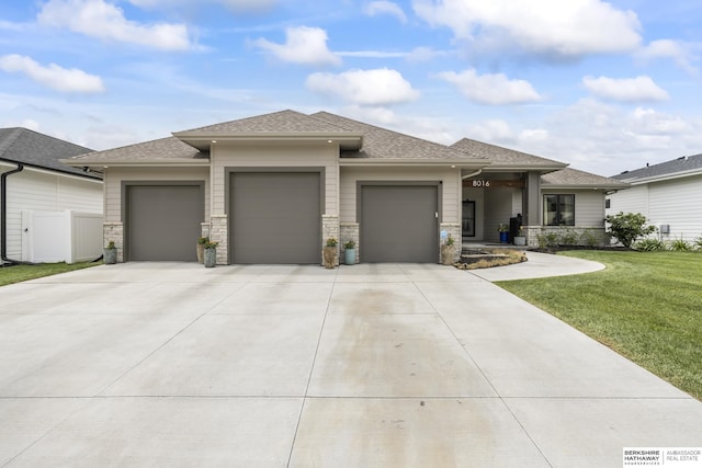 prairie-style house featuring a garage and a front lawn