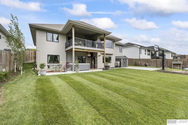 rear view of property featuring a balcony, a storage unit, a patio area, and a lawn