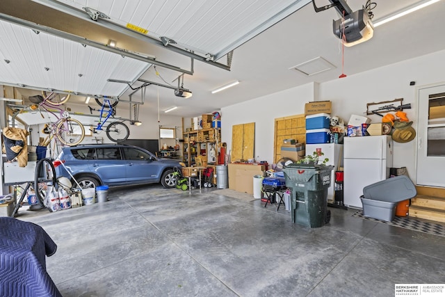 garage featuring white refrigerator and a garage door opener