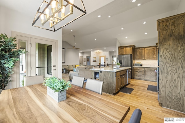 dining space featuring sink, light hardwood / wood-style floors, and vaulted ceiling