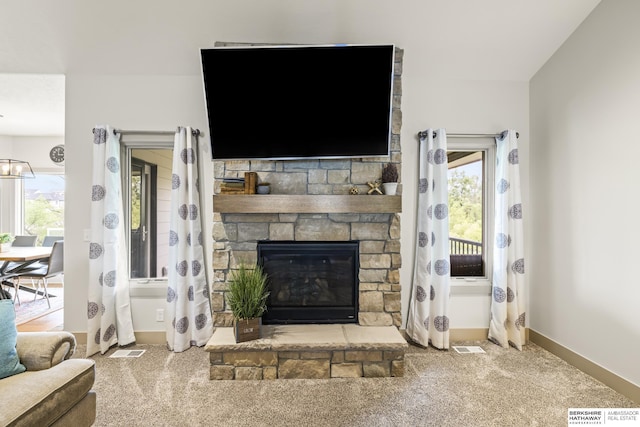 carpeted living room with a stone fireplace