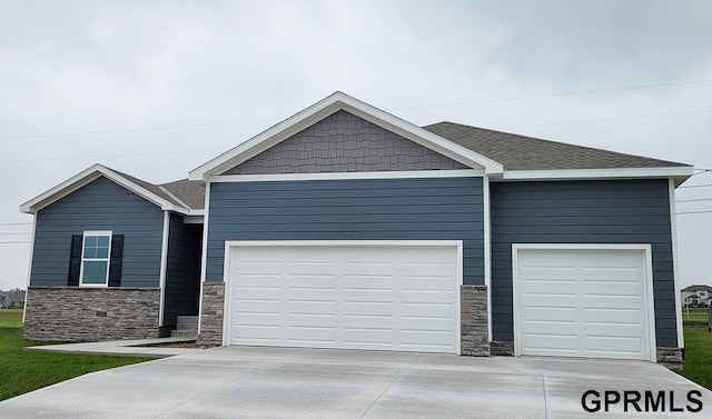 view of front facade with driveway, stone siding, and an attached garage