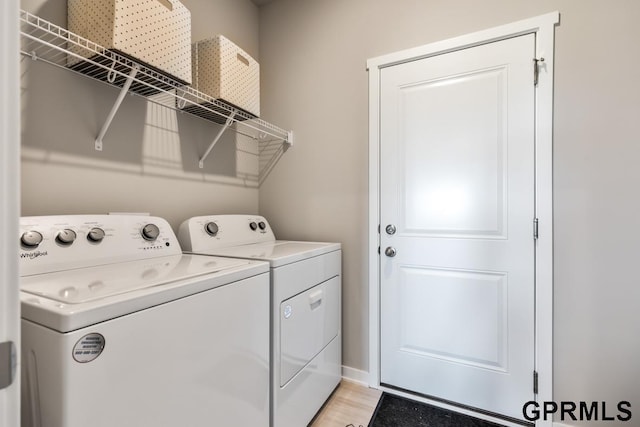 washroom with laundry area, light wood finished floors, and washer and clothes dryer