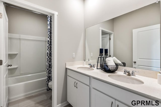 bathroom featuring double vanity, shower / bathtub combination with curtain, toilet, and a sink