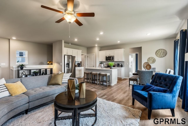 living room with a ceiling fan, recessed lighting, and light wood finished floors