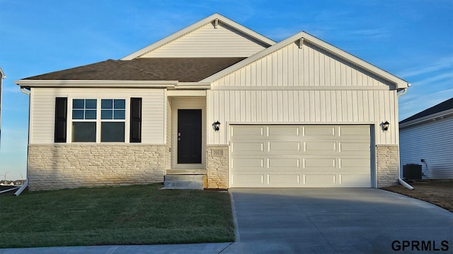 view of front of home with a front lawn, central AC unit, and a garage