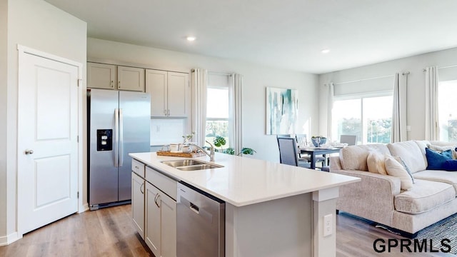 kitchen featuring an island with sink, stainless steel appliances, light wood-type flooring, and sink