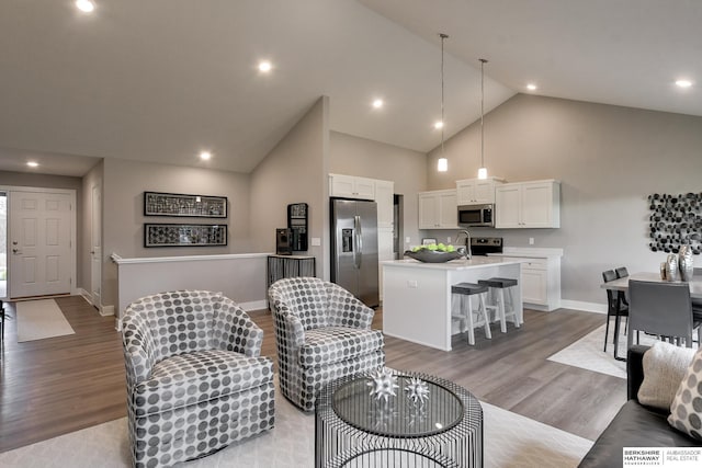 living room with high vaulted ceiling, light wood-style flooring, and baseboards