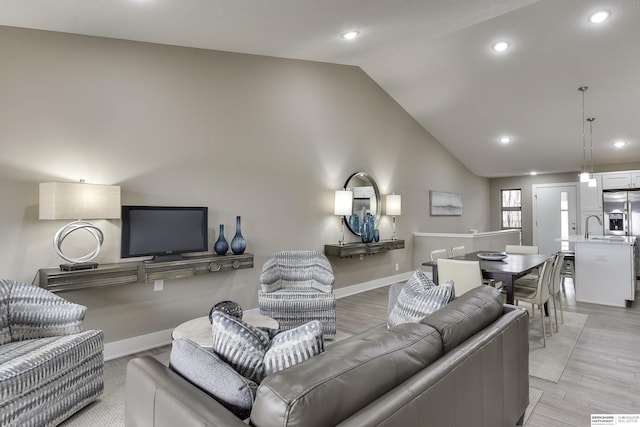 living area featuring high vaulted ceiling, recessed lighting, baseboards, and light wood finished floors