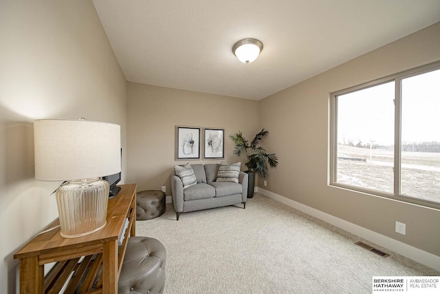 living area featuring light colored carpet, a healthy amount of sunlight, visible vents, and baseboards