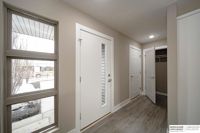 foyer featuring a textured ceiling, wood finished floors, and baseboards