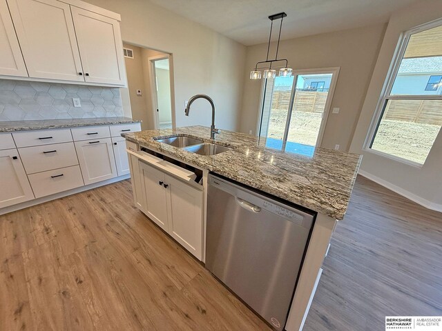 kitchen with stainless steel dishwasher, white cabinets, light wood-style floors, and a sink