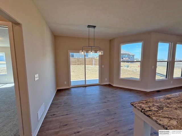 unfurnished dining area featuring dark wood-type flooring, baseboards, and visible vents